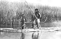 Two Native American people on a boat on a river